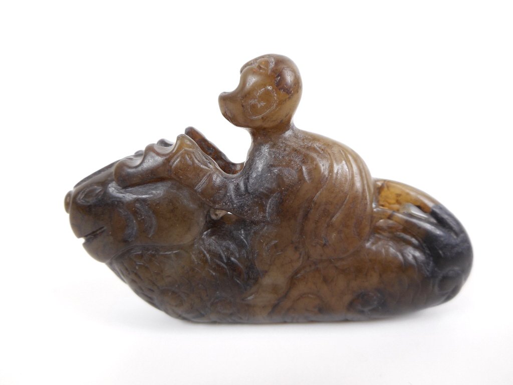 Jade Figure Riding Mythological Beast: Jade carving of a male figure riding a mythological beast. Incised details, dark brown and black suffusion with slight surface erosion observed in darker areas. 1.5"H x 2.5"W