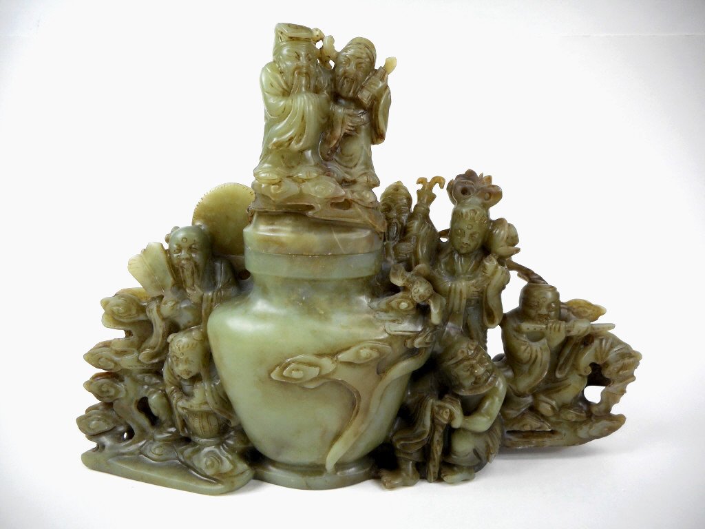 Jade Lidded Vessel: Green jade lidded vessel in detailed openwork carving, featuring scholars, musicians, court figures, auspicious animals and symbols. Russet brown and white suffusion. 8"H x 11"W