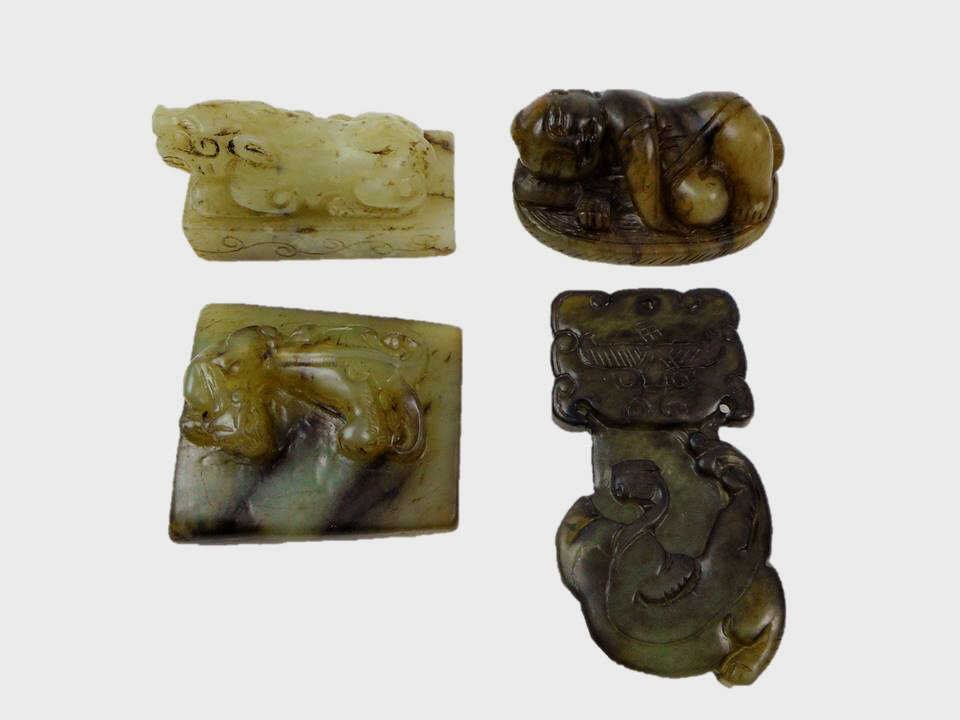 Four Jade Seals and Amulets: Collection of four jade seals and amulets of various form and age. One of white jade featuring a recumbent lion with dark brown suffusion. 1.5"H x 2"W One recumbent figure in greenish-white jade with 