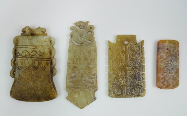 Chinese Jade Ornaments and Axe: Three Chinese jade ornaments bearing anthropomorphic mask designs, and one jade axe surmounted by a crouching lion figure. Largest measures 4.75"L Provenance: Private Massachusetts collection.
