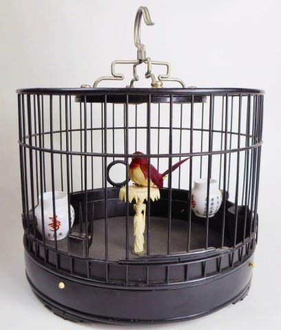 Antique Chinese Black Lacquer Birdcage: Black lacquer drum shaped antique Chinese birdcage with carved bone perch fashioned in the form of a woman holding a parasol. The cage is secured to base with four pins comprised of bone. There are tw