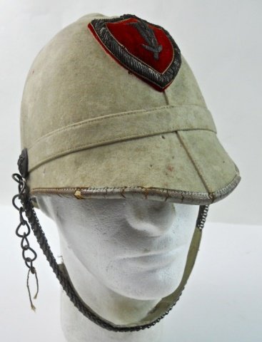 Early 20th C. British Pith Helmet: White canvas covered cork body with vented crown and chin scale secured by buttons bearing lily and "U.P." Bullion velvet shield form badge with lily. Interior with leather sweatband. Losses to leathe