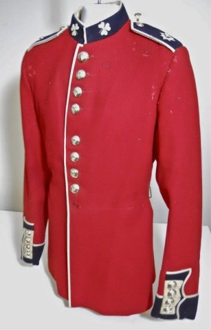 20th C. British Irish Guard's Parade Tunic: Red wool construction with white piping. Nine button front closure with silvered buttons bearing crowned harp emblem. Blue stand up collar with embroidered clover insignia. Four button cuffs with eigh