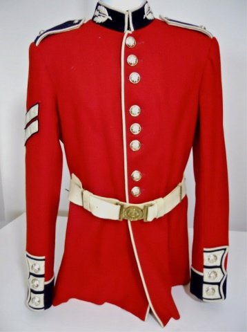 20th C British Scotts Guards Parade Tunic and Belt: Red wool construction with white piping. Nine button front closure with hooked stand up collar with thistle device. Blue and white shoulder boards, two chevron sleeve rank insignia with three button c