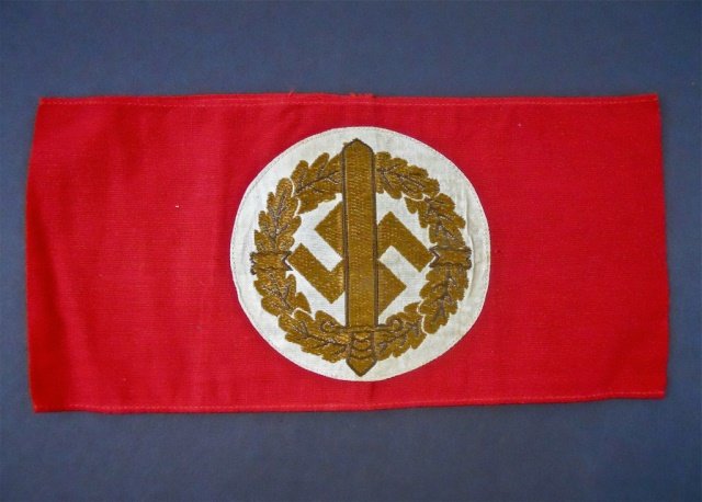 WWII SA Sports Armband, Paper RZM Tag: Red cotton construction with white medallion, sword and swastika in oak leaf wreath in gold bullion thread. Interior paper RZM tag. Letter B with ink stamped number and letter T, No. 329810 printed.