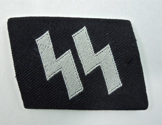 WWII SS EM/NCO Runic Collar Tab: BeVo woven double Sig rune in silver on black background. Fabric is folded over cardboard backing. 4.6" H x 2.2" W