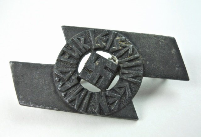 WWII German Deutsche Jungend Proficiency Badge: Die struck alloy depicts central swastika with radial runic script superimposed on a Sig rune with soldered pin back in brass wire. 1.8"H x .9" W. 10.5g