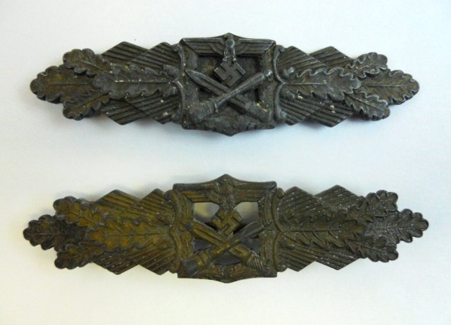 Two WWII German Close Combat Clasps: Die struck alloy with bronze finish depicts crossed bayonet and stick grenade in oak leaf frame surmounted by spread winged eagle clutching canted swastika with radiating oak leaf cluster and rays. Re
