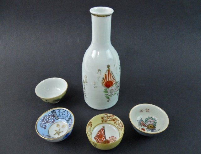 WWII Imperial Japanese Sake Set (5pc): Five piece lot includes: 6.2" H decanter, with hand painted Imperial flag, cherry blossoms and poem, "Yamato Spirit." Four hand decorated sake cups measuring 2.2" depict various military and patriotic