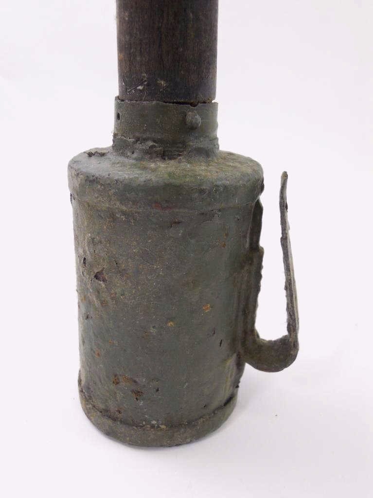 INERT WWI German M1915 Stick Grenade: Steel head with belt hook, wooden shaft with threaded end cap. Thick green olive drab painted metal surfaces. Measures 14"L x 2.75" D. Heavily oxidized under what appears to be field applied war paint