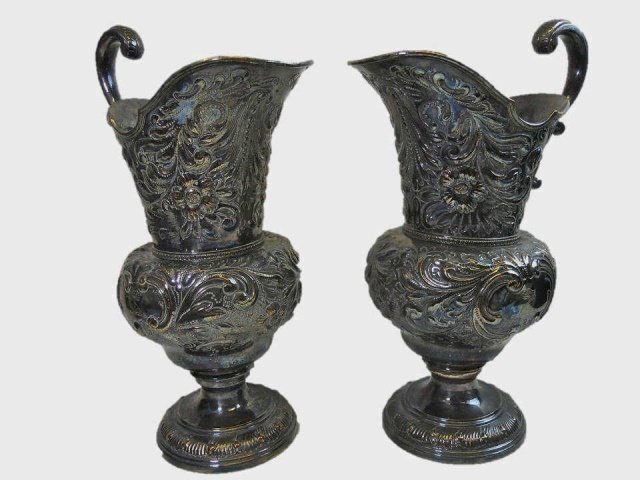 Two Antique Silver Plated Ewers: Two elaborately chased repousse antique silver plated ewers in floral and foliate design, bearing engraved Baronial Crest. surface loss at high points. Measures 17" H.