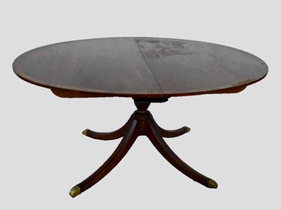Antique Banded Mahogany Dining Table, BAKER: Oval expandable dining room table in mahogany with brass footed "Duncan Phyfe" style base. Figured mahogany top with inlaid wood decorative band. Adjustable for three additional leafs, underside carri