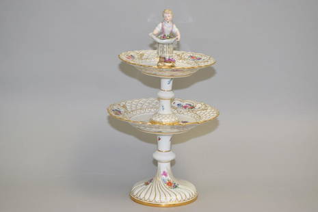 19th C. Meissen Porcelain Two-Tier Cake Stand: 19th C. Meissen porcelain two-tier cake stand, hand painted open work tiers with flower and butterfly decoration, the knop in the form of a child. Blue cross mark. 9.25in by 16in.