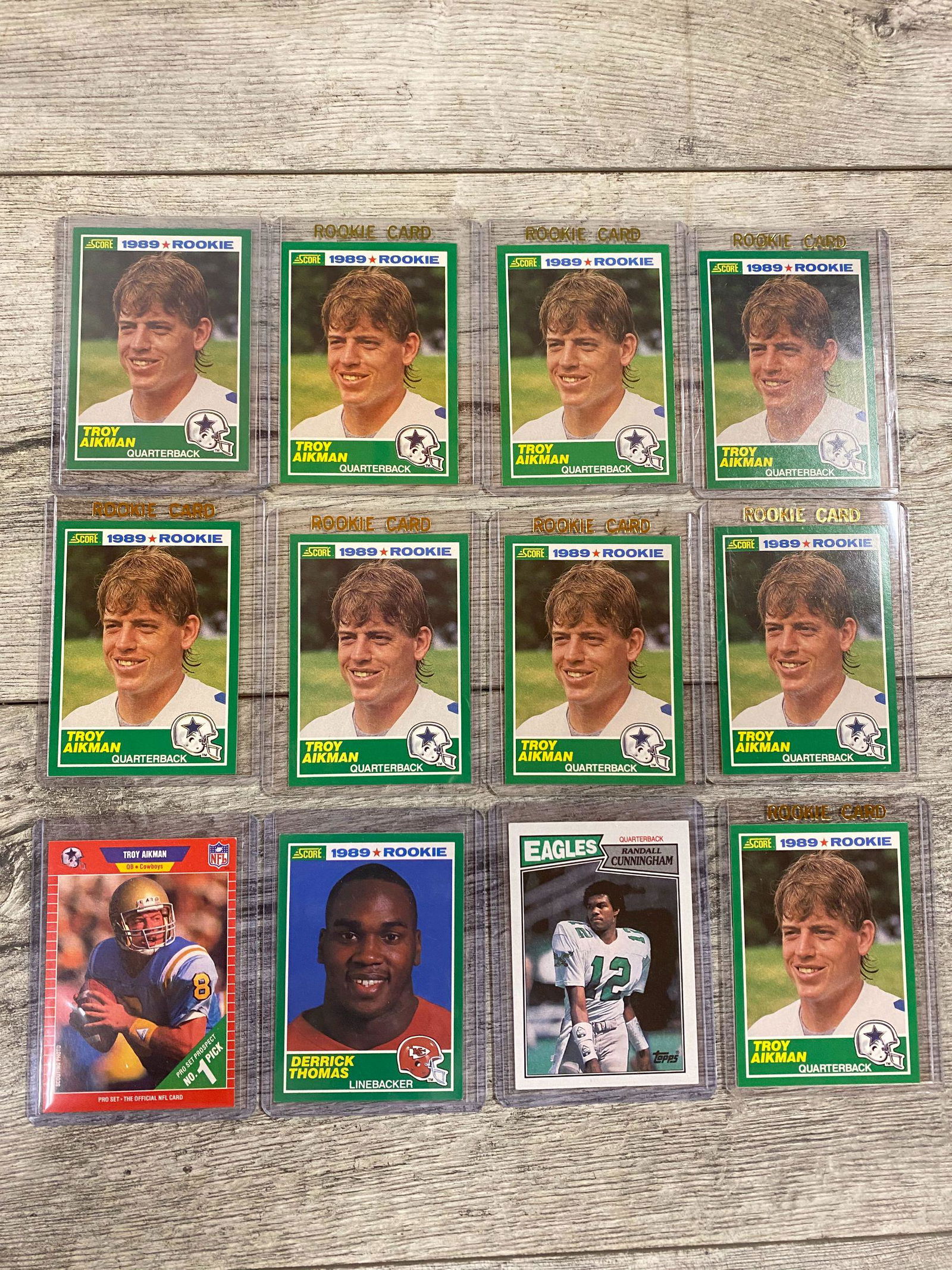 Lot of 1980s Football Cards, Stars, HOFs, and RCs: Troy Aikman rookie cards; nine 1989 #270 Score Aikman cards and one #490 Pro Set,; one Derrick Thomas Score 1989 rookie card, one Randall Cunningham 1997 Topps 296 . SOLD AS IS. BUYER ASSUMES ALL RISK