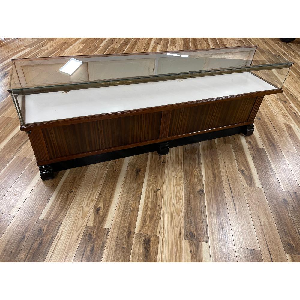 1920s to 1930s Solid Mahogany Display Case: Brass covered lighting, sliding back doors, storage drawers, original hardware and glass. 95.75 Inches L x 37 Inches T x 22.25 Inches D.