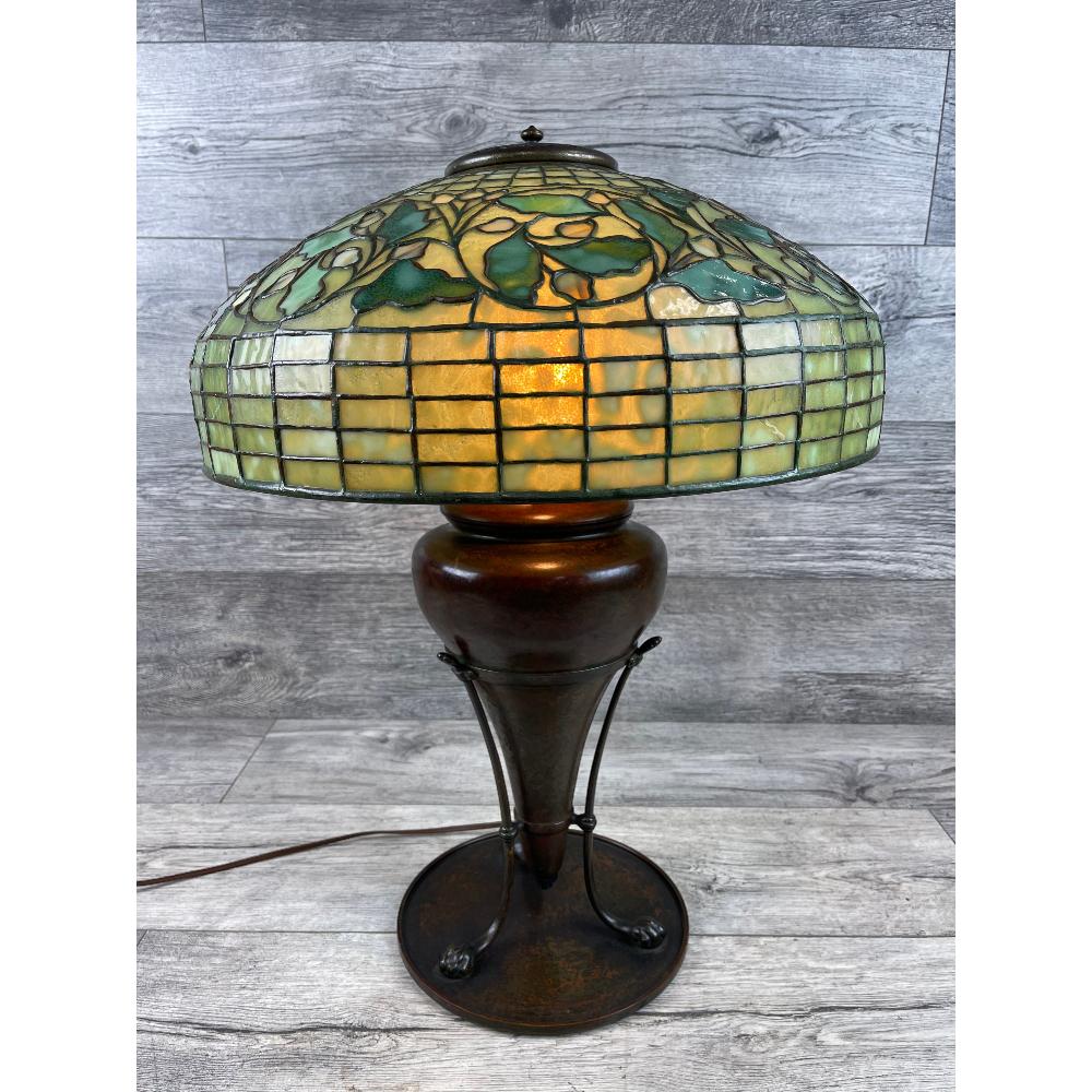 Tiffany Studios Acorn and Oak Leaf Table Lamp, Signed: Beautiful leaded shade has molted green glass in the geometric upper and lower panels. The center band of oak leaves and acorns are constructed in a multitude of greens. The shade is signed Tiffany St