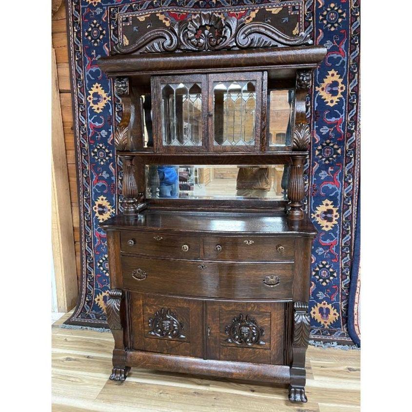 SUPERIOR OAK SIDEBOARD/BAR: Bevel mirrors, leaded glass doors, claw feet. Heavily decorated carvings and crown. Estate found condition. Approx. 85in T x 48in W x 23in D