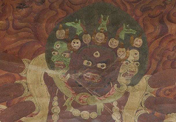 A 17th/18th Century or Later Thangka of Mahakala: The red skinned six armed Mahakala standing on a golden platform surrounded by a halo of fire. Each of the six hands holding a different Buddhist symbolic implement. No fabric border. 20 inches high x