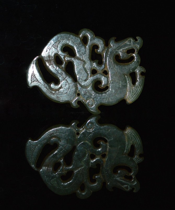 A Very Early Green Jade Dragon: Very thin with cut marks on either side, the serpentine dragon with flared tail. 3 inches in length.
