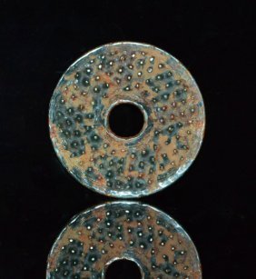 Zhou Dynasty Grass Green Bi: Finely done, grass green, partially calcified Bi, with the rice pattern on front and back, an articulated lip at the central hole and outer edge, scraping marks. 2.25 inches dia.