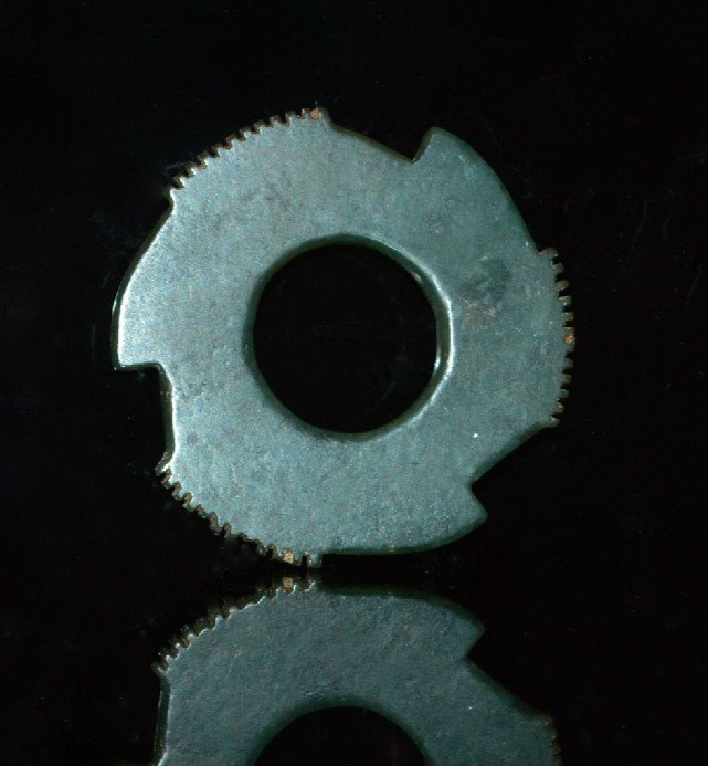 Zhou Dynasty Jade Astronomical Symbol: 12 teeth on three raised outer sections separated by a notch on one side and a raised fin on the other, a blueish green jade stone. 2.5 inches dia.