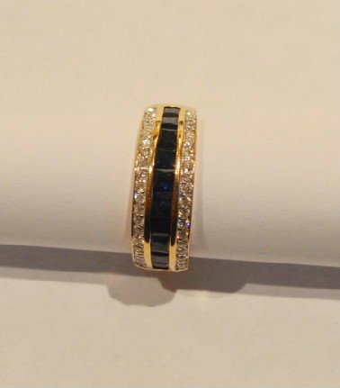 Sapphire and Diamond Gold Ring: Square cut Sapphires bordered on either side by rows of diamonds on a gold ring. Size 6 1/2. 14k gold with 10 square cut sapphires [+- 2.5 cttw] and 40 diamonds boardings the sapphires, 20 diamonds to