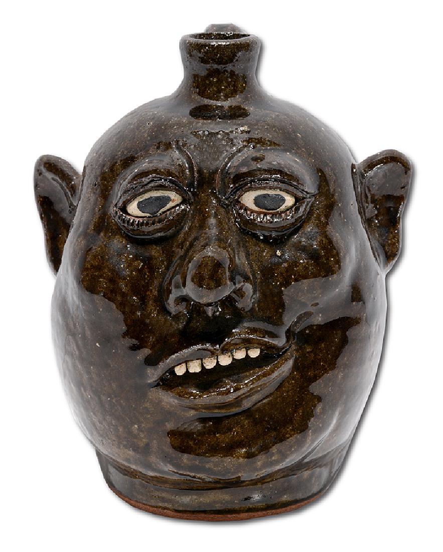 Lanier Meaders. Small Crooked Smiling Face Jug.: Lanier Meaders. Small Crooked Smiling Face Jug. c. 1980. Dark glaze. Mint condition. 8.5" h. Est. $800-1,200. Ship: $45