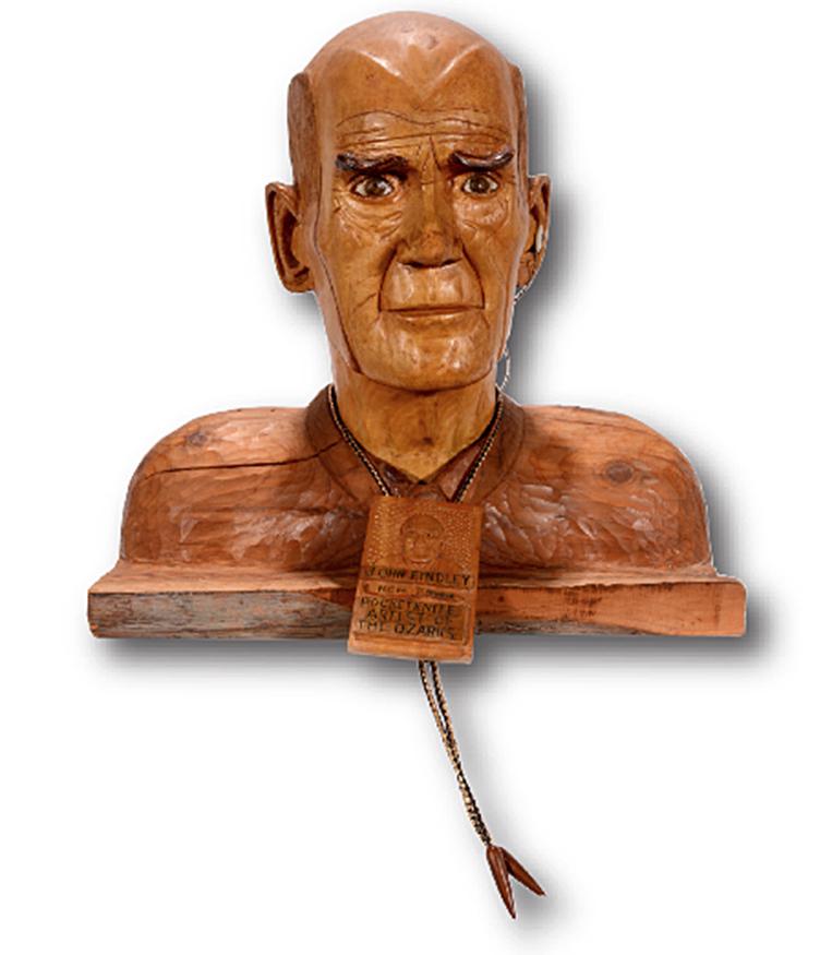 John Findley. Self-Portrait With Bolo Tie.: John Findley. Carved Self-Portrait With Bolo Tie. Signed. Not dated. Carved wood with mixed media ear piece and bolo tie. Minor natural wood split, otherwise great condition. 15"h x 15" x 9". Est.$800