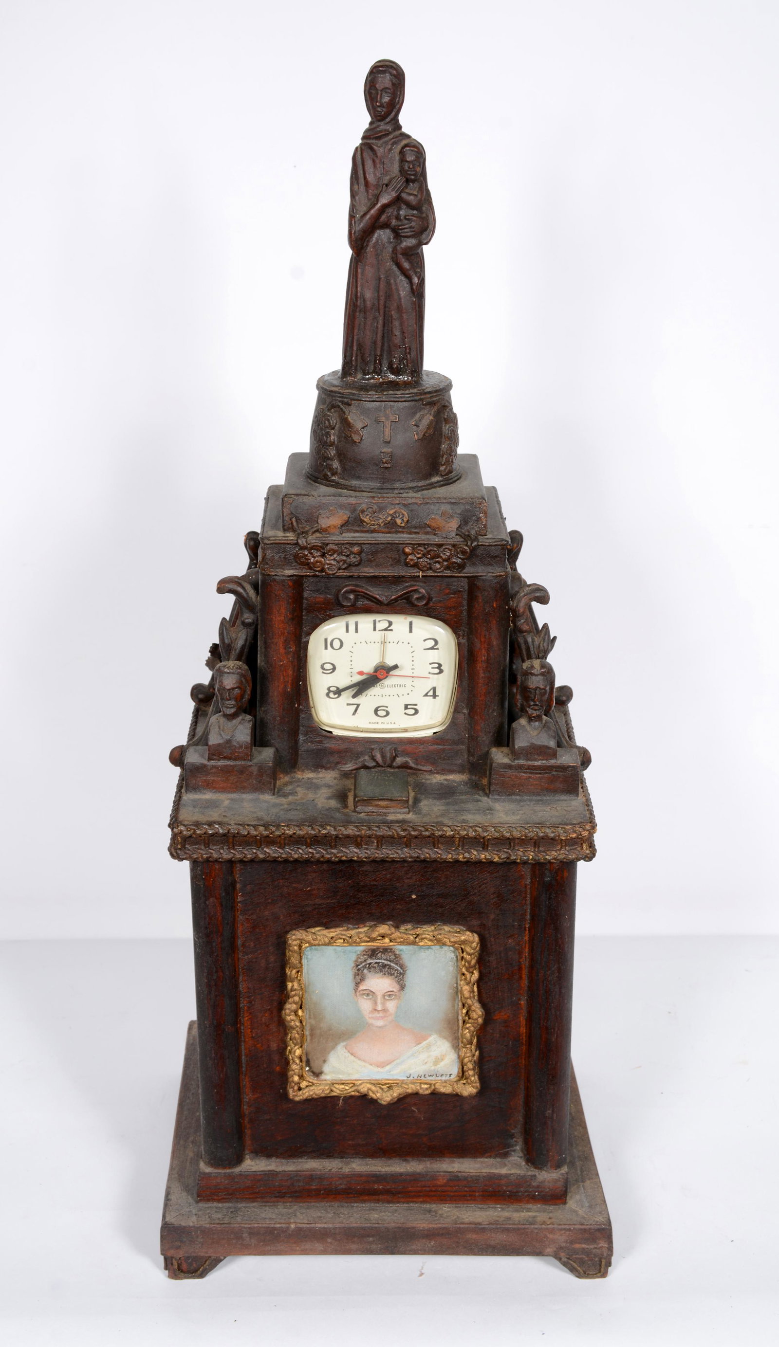 Rev. Joel D. Hewlett. Religiously Inspired Mantel: Rev. Joel D. Hewlett. Religiously Inspired Mantel Clock. Signed in portrait at bottom. Carvings include women with baby at top, two busts, a Bible and two praying women with 1940 electric clock in cen