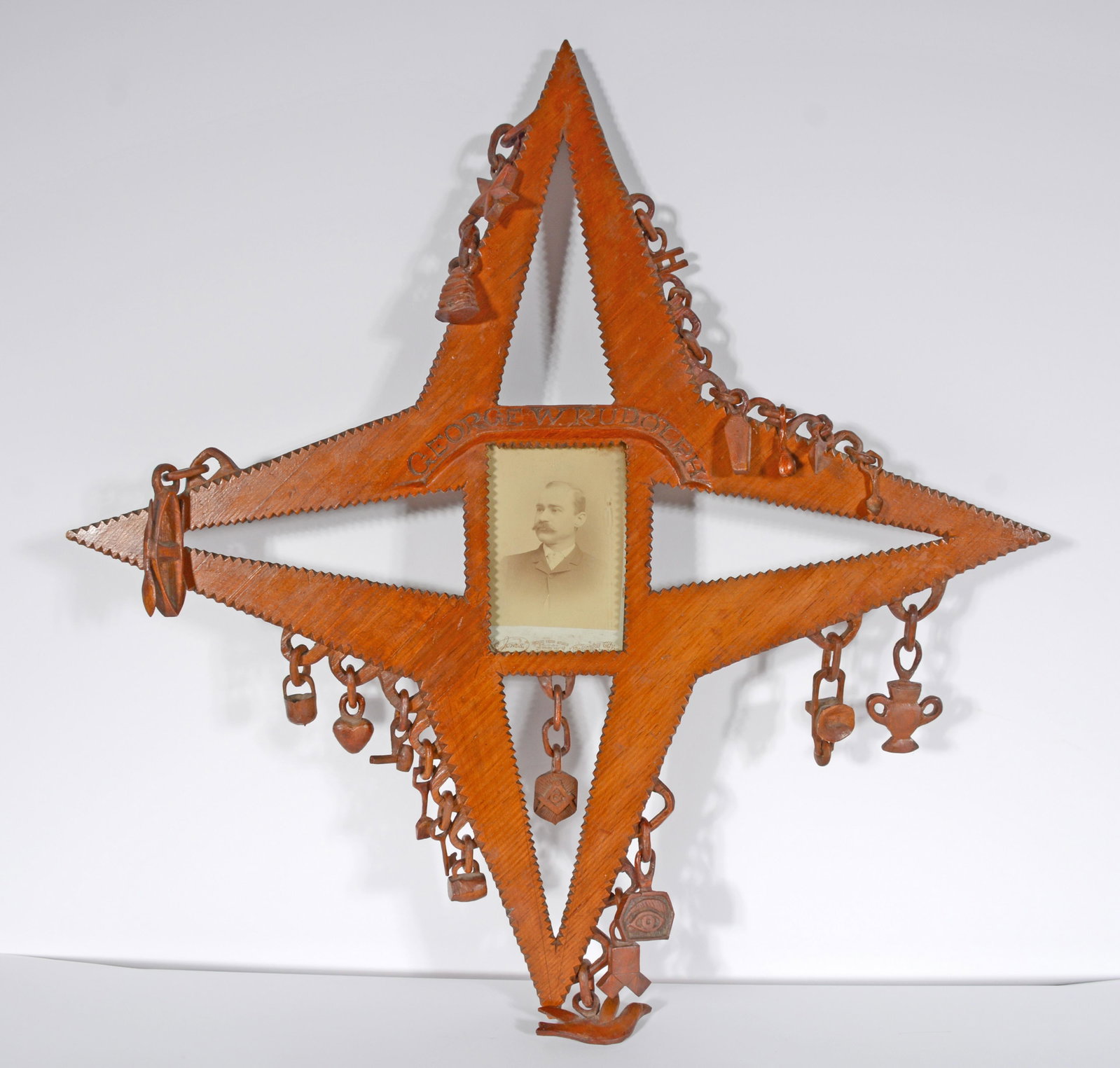 Odd Fellows Lodge Hall Star Whimsey With Symbols.: Odd Fellows Lodge Hall Star Whimsey With Symbols. Framed photograph, R. Jones Studio Card of George W. Rudolph, Columbia City, Indiana. Carved wood with varnish. Name is carved in wood. 28" h x 26" x 