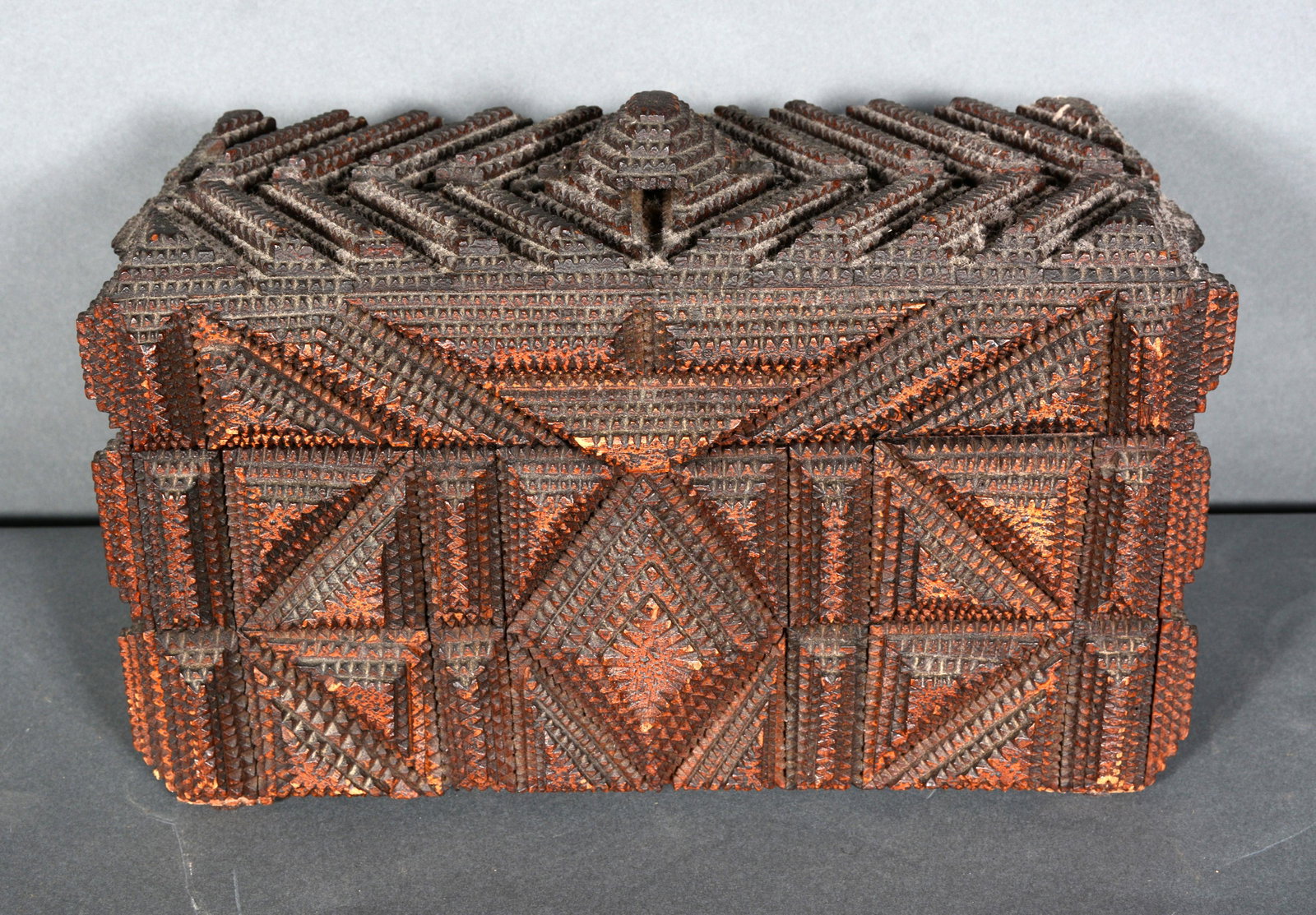 Intricately Carved Tramp Art Pyramids & Rectangles Box.: Intricately Carved Tramp Art Pyramids & Rectangles Box. c. 1900. Carved and stained wood with red fabric inside. Excellent condition. 9.5" x 14.5" h x 6.5" d. Provenance: ex. The Jeff Louis Tramp Art 