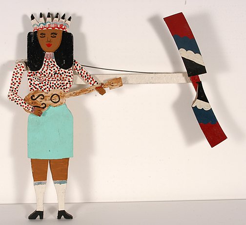 James Harold Jennings. Guitar Girl Whirligig.: Guitar Girl Whirligig.Paint, wood, plastic with metal hardware. Signed. 31"x 26" x 3.5". When blade turns, girl strums her guitar. Early piece. One blade has a missing corner. The Lynne Ingram Collect