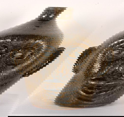 Lanier Meaders Early Glazed-Eye Face Jug.: Tobacco-spit glaze. c. 1970's. Perfectly-even glaze all the way around the jug. No teeth. Mint condition. 8.5"h. Est. $2,000-3,000. Ship: $50