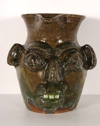 B.B. Craig Face Pitcher.: Face Pitcher. Hand-dug clay. c. mid 1980's. Beautiful ash glaze with traces of routille, china teeth, heavy eyebrows. Stamped, "B.B. Craig, Vale, NC." 7" h. Mint condition. Provenance: The Salvatore S