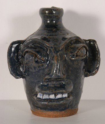 B.B. Craig Small Blue Face Jug.: Small Blue Face Jug. Hand-dug clay with cobalt blue glaze, china teeth, single eyebrow, elongated ears. Stamped, "B.B. Craig, Vale, NC." 6.5" h. c. mid 1980's. Mint condition. Provenance: The Salvator