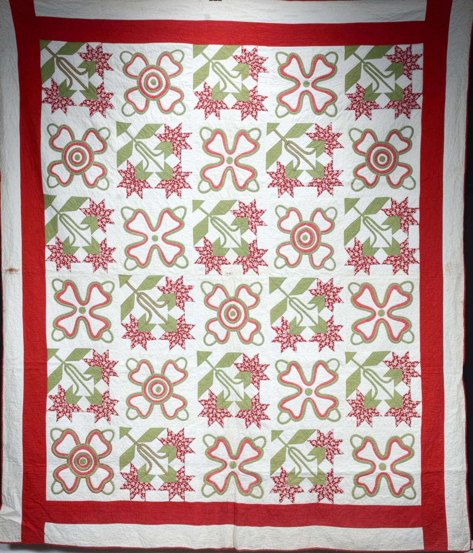Poinsettia and Clovers Quilt.: Anonymous. Poinsettia and Clovers Quilt. c. 1930-40's. Hand-stitched cotton. Minor staining on side and back, otherwise good condition. 75" x 87". Est. $300-500. Ship: $45