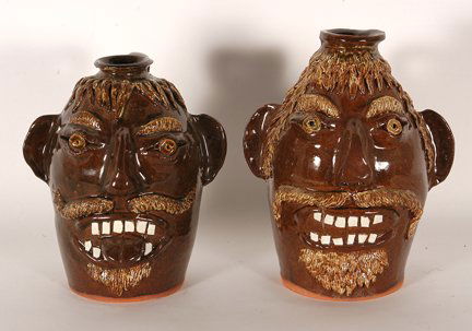 Albert Hodge. Sorgum Spout Face Jugs.: Albert Hodge. Pair of Sorgum Spout Face Jugs. Early face jug brown glaze with china plate teeth. 10.5”h. Signed. Mint condition. Est. $200-400. Ship: $65