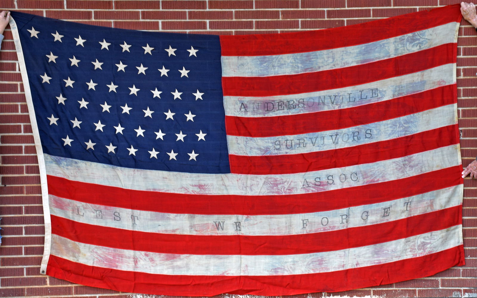 Andersonville Prison Survivors Association. LEST WE FORGET. 45 Star Linen Flag. 1896-1908.: Andersonville Prison Survivors Association. LEST WE FORGET. 45 Star Linen Flag.1896-1908. Andersonville Prison. Linen. brass grommets; legend stenciled on the white areas between the red stripes; some