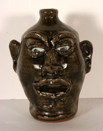 Lanier Meaders. Face Jug With Lazy Eyes.: Lanier Meaders. Face Jug With Lazy Eyes. c. mid 1980’s. Signed. Ash glaze. Melted teeth and slightly melted eyes. Mint condition. 10”h. Est. $1,000-1,200. Ship: $45