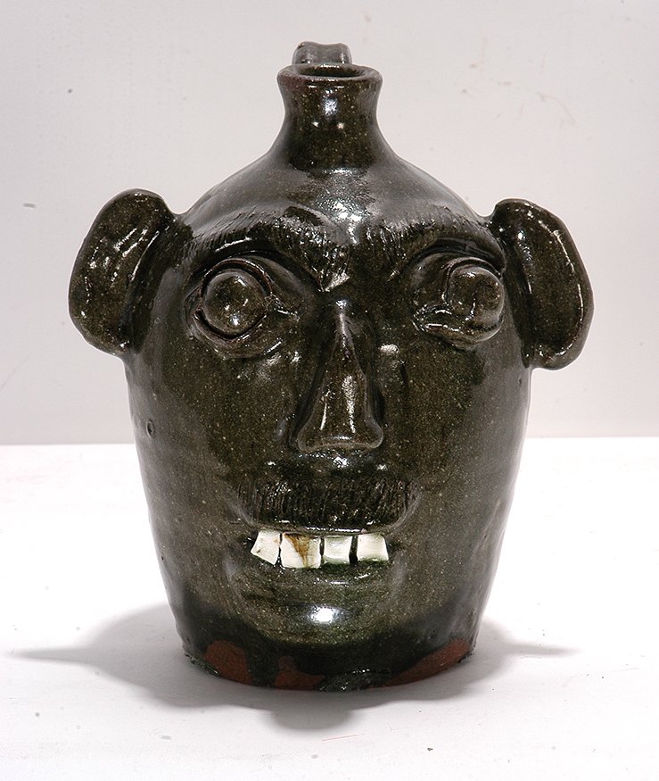 B.B. Craig. Bug-Eyed Face Jug.: B.B. Craig. Bug-Eyed Face Jug. c. 1970-80’s. Stamped, “B.B. Craig Vale, N.C.” Ash glaze. Wood-fired hand-dug clay. Mint condition. 10”h. Provenance: ex. Bishop / Johnson Collection. Est. $1,00