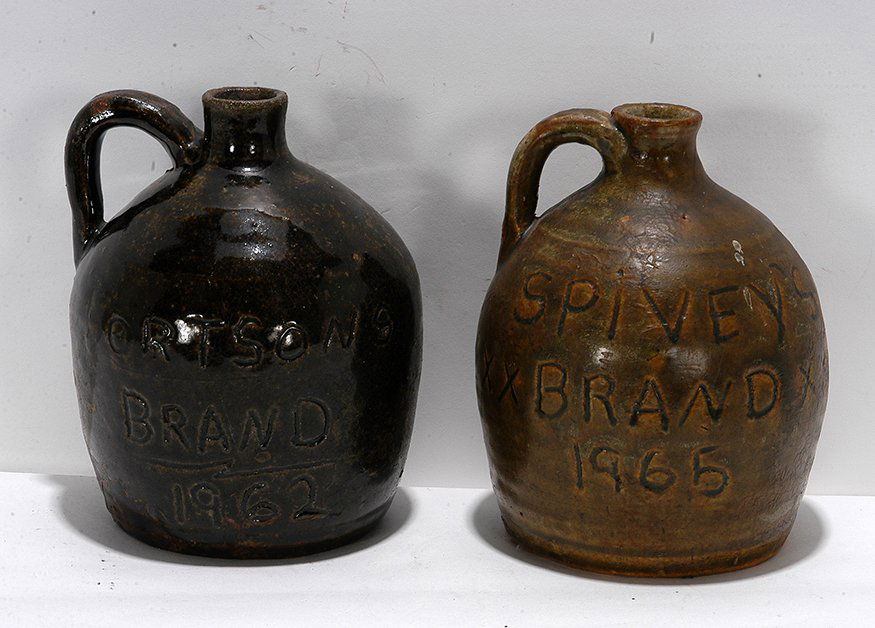Cheever Meaders. Fortson’s & Spivey’s Brand Whiskey: Cheever Meaders. Fortson’s & Spivey’s Brand Whiskey Jug. 1962 & 1965. Intialed on bottom with “C.M.” Script on side with dates. Both appear to have been repaired and reglazed, otherwise good c
