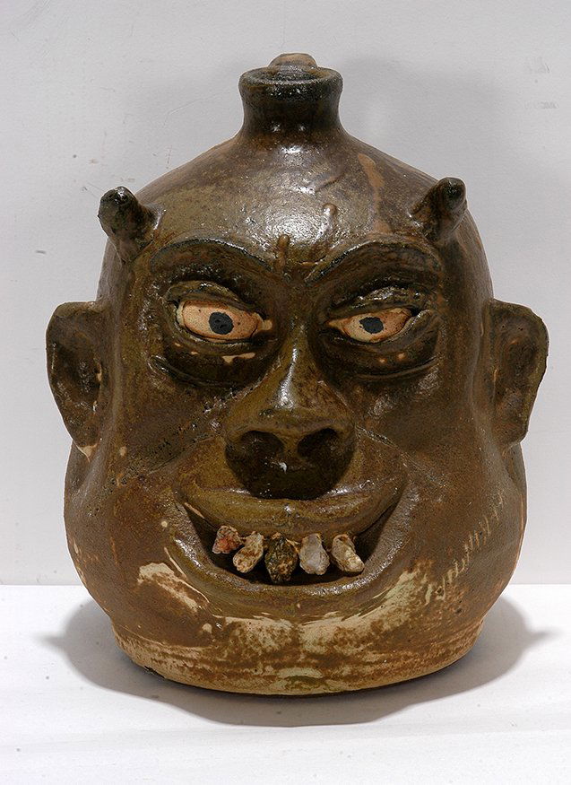 Lanier Meaders. Fat Jowel Rock Tooth Devil Face Jug.: Lanier Meaders. Fat Jowel Rock Tooth Devil Face Jug. c. 1960’s-70’s. Signed. Large rock teeth. Low-fire matte glaze, incised scar and stitches on face. Excellent condition. 10”h. Provenance: A p