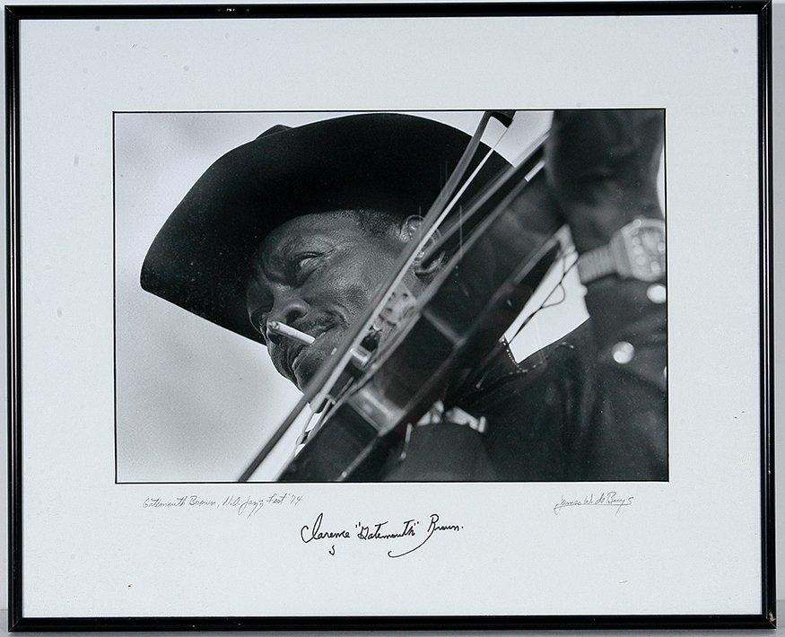 Clarence Gatemouth Brown. Photograph w Signature,: Clarence Gatemouth Brown (1924-2005). Photograph with Signature.Signed on frame matting by Brown and by photographer, James W. DeBuys, 1974 Jazz Fest, New Orleans, LA. Photo is 13” w x 9”. Est. $8