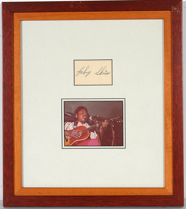 Johnny Shines. Photo With Signature Card.: Johnny Shines (1915-1992). Photo With Signature Card. Photo is 4” x 3”. Signature card is 2.5” w x 1.5” h. Frame is 12” x 14”. Est. $200-400. Ship: $35. Inspired by Robert Johnson, inducte