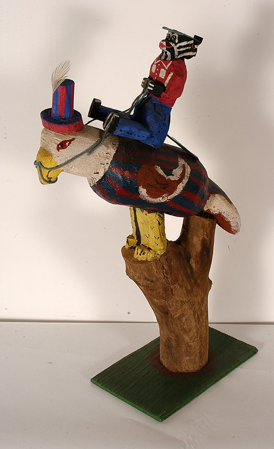 Delbert Buck. Skunk Riding Patriotic Eagle.: Delbert Buck. Skunk Riding Patriotic Eagle. Not signed or dated. Carved and painted wooden logs. Great condition. 29”h x 21” x 8”. Est. $200-400. Ship: $85