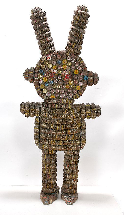 Clarence Woolsey. Figure w Alien Headdress.: Clarence Woolsey. Figure With Alien Headdress.Not signed. Bottlecaps attached to wooden frame. Excellent condition. 19” x 13” x 45”h. Est. $3,000-5,000. Ship: $200