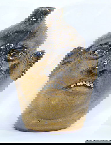 Lanier Meaders Tall Face Jug: Clay Teeth, c. mid 1980's. Half high and half matte glaze. Mint condition. 11" h. The back has a rough rock attached to glaze in the middle and on the bottom there is a spot of glaze missing, probably