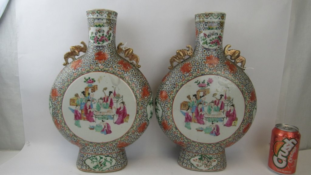 Pair of Chinese Canton Famille Rose Moon Flasks: 19th-20th Century; Each side decorated with figures in a ceremonial scene, the obverse with various butterflies and insects among blossoms, with bat-form handles Height: 16in.