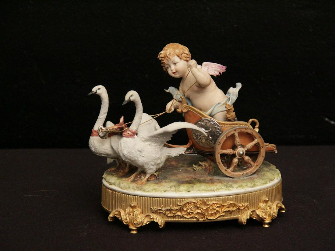 GRUPPO IN PORCELLANA: “CARRO CON PUTTO ALATO TRAINATO DA CIGNI”,XX° secolo,h cm 20 x 20