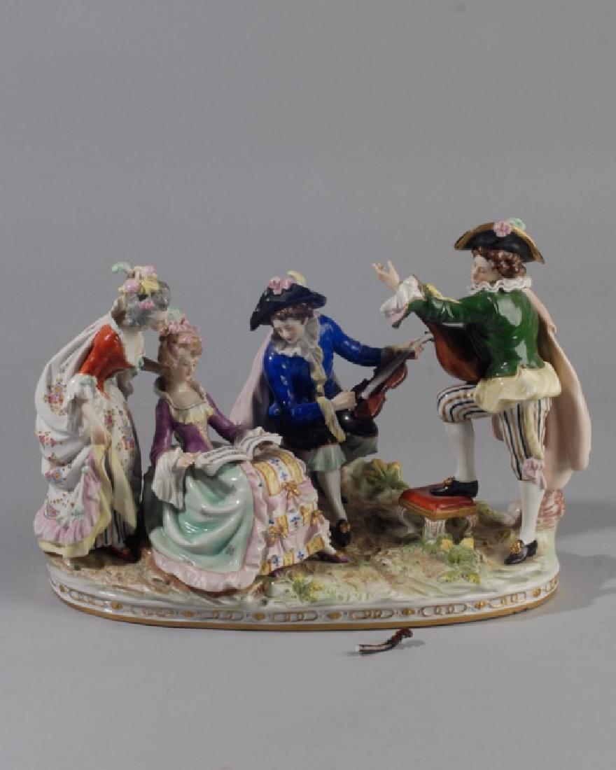 19th C. Continental Porcelain Figural Grouping: Probably Dresden, blurred mark to base, two figures with musical instruments together with a seated lady looking at sheet music with a fourth figure looking on. One musical instrument has been broken 